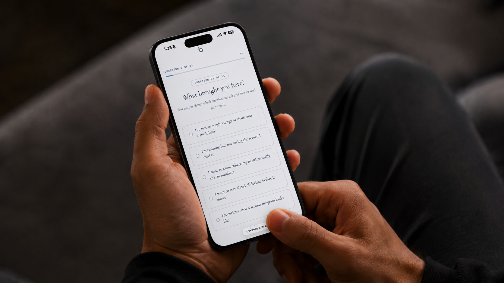Hand holding a phone showing the True Body health questionnaire